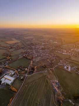 Aerial view of the village of Sap-en-Auge surrounded by rural fields and roads in the golden hour light in Sap-en-Auge, Normandy, France.