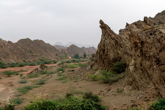 View of the rugged rock formations of the Sulaiman Mountains in an arid landscape with sparse desert vegetation in De-excluded Area Dera Ghazi Khan, Punjab, Pakistan.