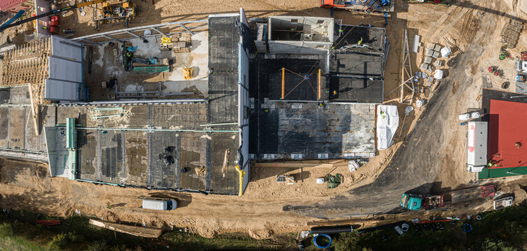Aerial view of a construction site with building foundations, concrete structures, construction materials, and heavy machinery in Latvia.