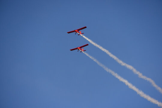 Druskininkai, Alytus County, Lithuania - 23 May 2026: View of two red airplanes performing an aerobatic maneuver with smoke trails against a clear blue sky.