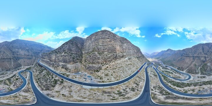 Aerial view of the winding mountain road and the Steel Bridge at Fort Munro, featuring dramatic rocky terrain and clear blue sky in Dera Ghazi Khan, Punjab, Pakistan.