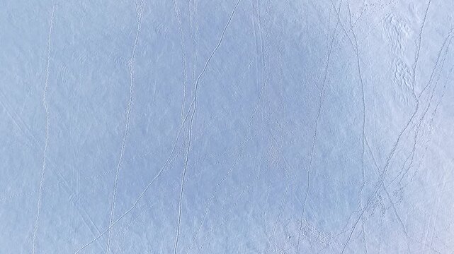 Aerial view of snow-covered landscape with intricate patterns of tracks across the pristine white surface in Latvia.