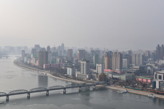 Aerial view of the Pyongyang cityscape featuring modern high-rise buildings along the Taedong River with a bridge in the foreground in Pyongyang, Pyongyang, North Korea.
