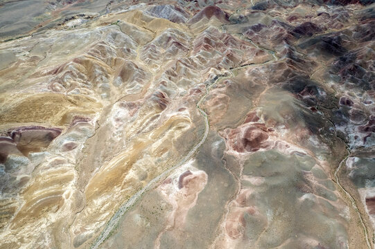 Tuzluca, Igdir, Turkiye - 04 July 2025: Aerial view of the colorful Tuzluca Rainbow Hills, showcasing vibrant mineral-rich slopes, winding dry riverbeds, and rugged terrain.