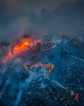 Pantoja, Dominican Republic - 29 April 2020: Aerial view of the fire at Vertedero Duquesa landfill, with an excavator working amidst smoke and flames as firefighters work.