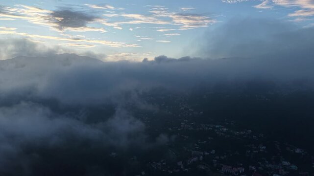 Aerial view of Nainital town partially obscured by thick mountain clouds during the early morning light in Nainital, Uttarakhand, India.
