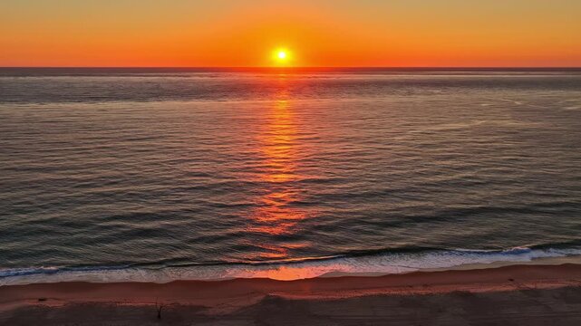 Aerial view of Dune of Pilat at sunset with golden light reflecting on the ocean waves in Nouvelle-Aquitaine, France.