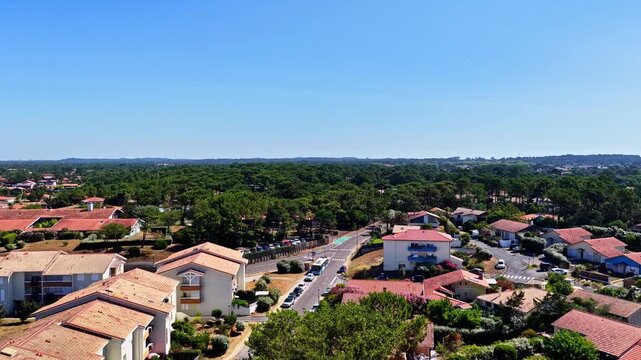 Aerial view of Plage des Oceanides in Capbreton, featuring residential buildings with terracotta roofs, lush pine forests, and clear blue skies in Capbreton, Nouvelle-Aquitaine, France.