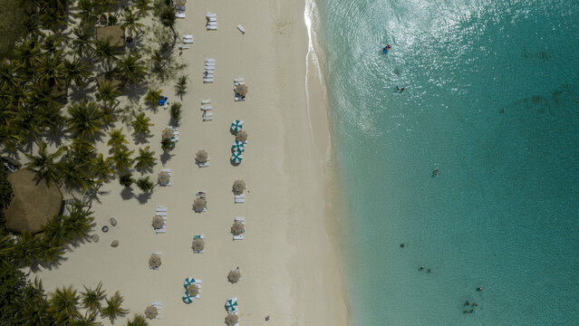 Aerial view of Old Fort Bay beach with white sand, turquoise water, palm trees, and beach umbrellas, Nassau, New Providence, The Bahamas.
