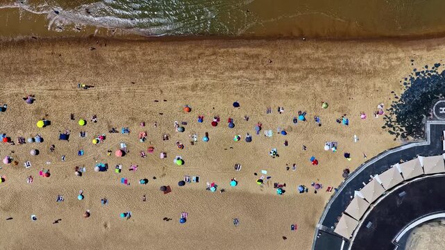 Aerial view of Port de Capbreton with beachgoers and colorful umbrellas on the sandy shore in Capbreton, Nouvelle-Aquitaine, France.