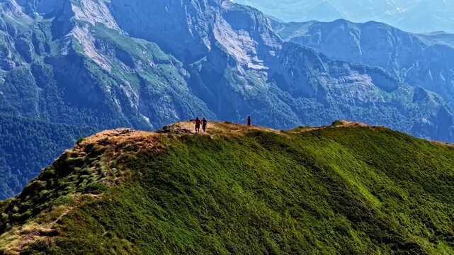 Aerial view of hikers walking along the green mountain ridge of Col d'Aubisque in Beost, Nouvelle-Aquitaine, France.