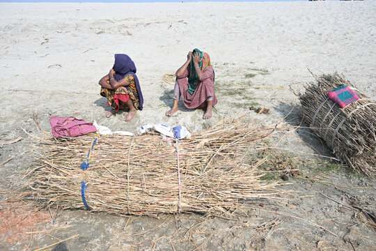 Gaibandha District, Rangpur Division, Bangladesh - 15 February 2026: View of two women sitting on the sandy banks of Char Krishnamani with bundles of collected firewood.