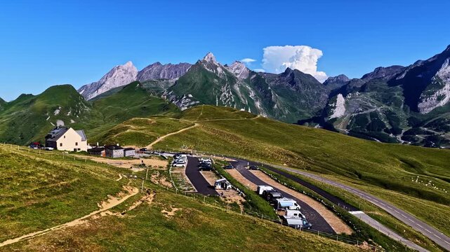 Aerial view of Col d'Aubisque with a winding road, parked vehicles, and green mountain slopes in Beost, Nouvelle-Aquitaine, France.