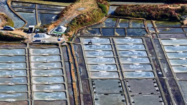 Aerial view of rectangular salt evaporation ponds with white salt piles and narrow dirt paths in Capbreton, Nouvelle-Aquitaine, France.