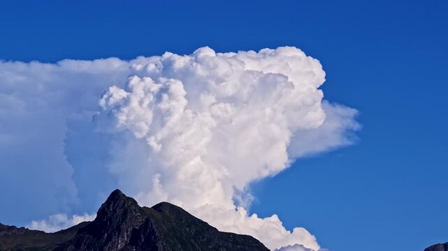 Aerial view of a large cumulus cloud rising above the mountain peaks of Col d'Aubisque in Beost, Nouvelle-Aquitaine, France.