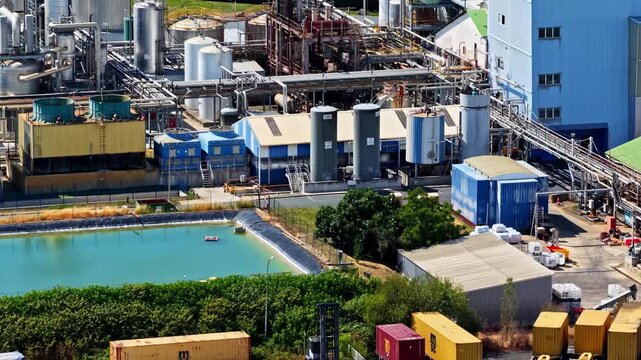 Aerial view of the Port of Bordeaux industrial facility featuring storage tanks, shipping containers, and a turquoise water basin in Bassens, Nouvelle-Aquitaine, France.