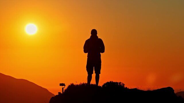 Aerial view of a silhouette of a person standing against a vibrant sunset sky at Col d'Aubisque in Beost, Nouvelle-Aquitaine, France.