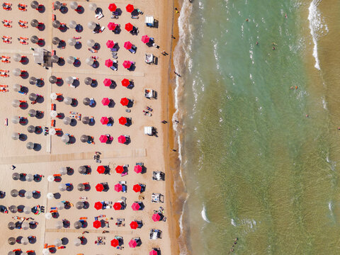 Aerial view of Zakynthos beach featuring rows of colorful sun umbrellas on the sand and clear turquoise water of the Ionian Sea, Zakynthos, Greece.