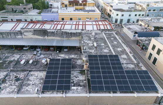 Aerial view of solar panels and industrial air conditioning units installed on a flat urban rooftop in the historic center of Merida, Yucatan, Mexico.