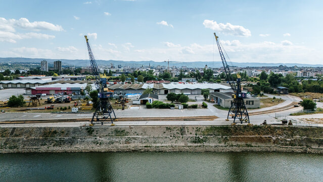 Aerial view of Luka Novi Sad port with industrial cranes, warehouses, and the Danube riverbank in Novi Sad, Vojvodina, Serbia.