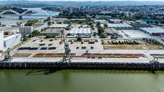Aerial view of Luka Novi Sad with industrial cranes, shipping containers, and warehouses along the Danube River in Novi Sad, Vojvodina, Serbia.
