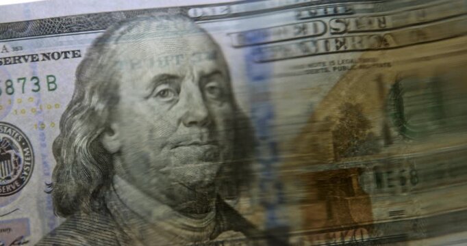 Volatility concept. Close-up studio video of a 100 US dollar banknote viewed through a wavy water surface, creating a distorted and fluid appearance. 