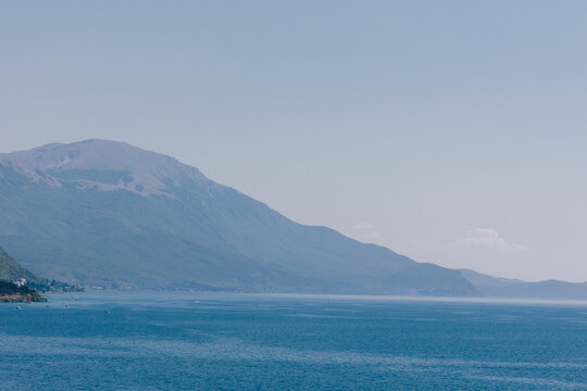 View of Lake Ohrid with mountains in the background under a clear blue sky, Komuna e Ohrit, North Macedonia.