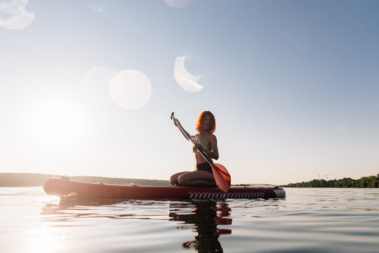 Woman enjoying stand up paddle boarding at sunset
