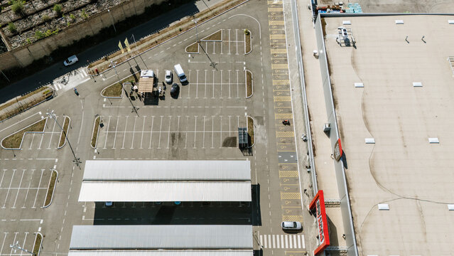 Aerial view of a parking lot with covered parking structures and a large retail building in Novi Sad, Vojvodina, Serbia.