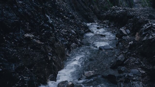 Fast flowing mountain stream rushing through rocky narrow gorge