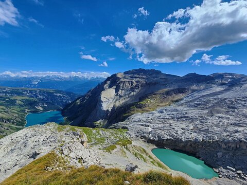 View of Lac de Tseuzier and surrounding turquoise alpine lakes nestled in the rugged rocky landscape of the Swiss Alps under a bright blue sky in Valais, Switzerland.