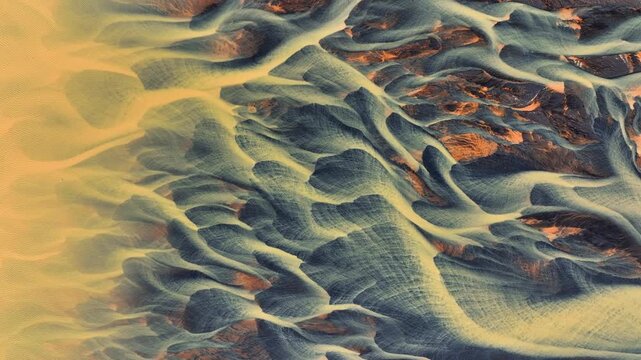 Aerial view of the intricate, braided patterns of a glacial river delta with sediment-rich water flowing through dark volcanic terrain in Selfoss, Sveitarfelagid Arborg, Iceland.