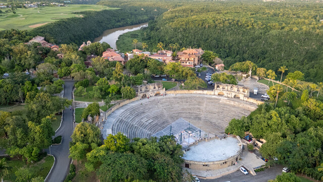 Aerial view of Altos de Chavon amphitheater surrounded by lush tropical vegetation, stone buildings, and the Chavon River in La Romana, La Romana Province, Dominican Republic.
