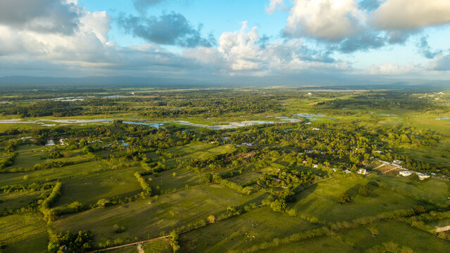Aerial view of the lush green landscape with winding rivers, agricultural fields, and scattered trees under a cloudy sky in Cabrera, Maria Trinidad Sanchez, Dominican Republic.