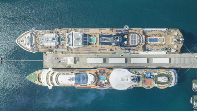 Aerial view of Nassau Cruise Port with two large cruise ships docked at the pier, featuring swimming pools, decks, and clear turquoise water in Nassau, Grand Bahamas, The Bahamas.
