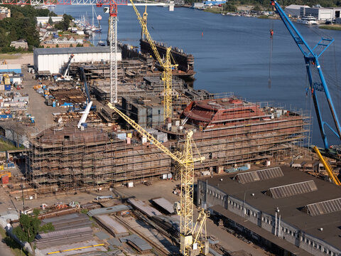 Aerial view of Conrad Shipyard with a large vessel under construction surrounded by scaffolding and yellow cranes along the waterfront in Gdansk, Wojewodztwo pomorskie, Poland.