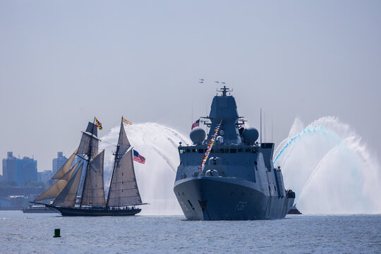 Jersey City, New Jersey, United States - 04 July 2026: View of a modern naval frigate and a classic sailing ship during a ceremonial water salute at Liberty State Park.