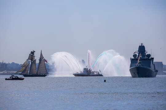 Jersey City, New Jersey, United States - 04 July 2026: View of a tall ship, a fireboat performing a water salute, and a naval warship on the water near Liberty State Park.