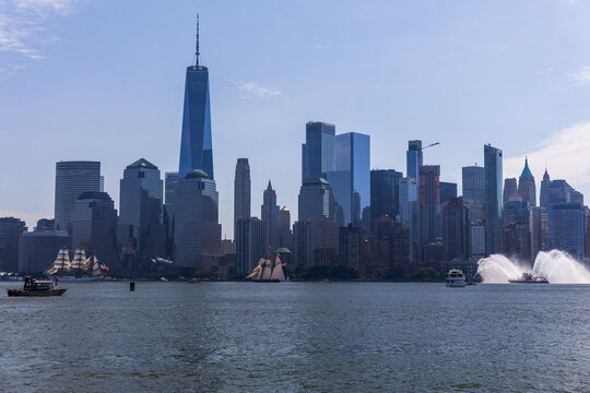Jersey City, New Jersey, United States - 04 July 2026: View of the Manhattan skyline with One World Trade Center, sailing ships, and a fireboat spraying water on the Hudson River.
