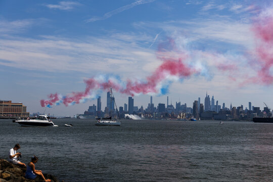 Jersey City, New Jersey, United States - 04 July 2026: View of Liberty State Park with people on the shore, boats on the river, and smoke trails over the New York City skyline.