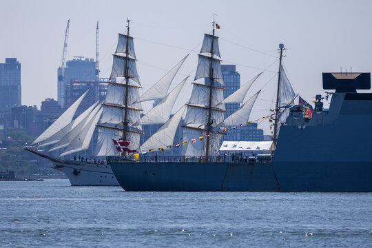 Jersey City, United States - 04 July 2026: View of the tall ship Danmark sailing alongside a modern naval vessel with the Jersey City skyline in the background.