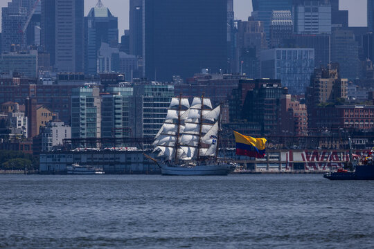 Jersey City, New Jersey, United States - 04 July 2026: View of a tall ship with white sails and a Colombian flag sailing on the water with the Jersey City skyline in the background.