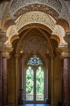 Sintra, Portugal - 14 July 2026: View of the ornate Moorish-style arches and intricate stucco details inside the Park and Palace of Monserrate, with a view of the lush garden beyond.