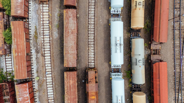 Aerial view of a train yard with various freight train cars including tanker cars and boxcars parked on parallel tracks in Novi Sad, Vojvodina, Serbia.