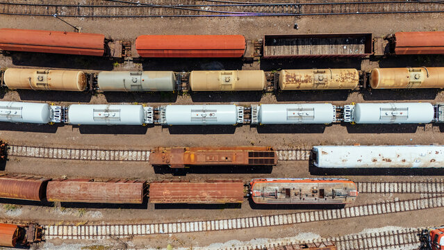 Aerial view of a busy train yard featuring rows of colorful freight cars, tanker wagons, and locomotives parked on parallel tracks in Novi Sad, Vojvodina, Serbia.