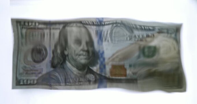 Volatility concept. Close-up studio video of a 100 US dollar banknote viewed through a wavy water surface, creating a distorted and fluid appearance. 