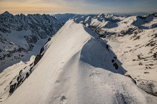View of Temne Smreciny valley from the snowy ridge of Koprovsky stit with dramatic mountain peaks and winter landscape in Vysoke Tatry, Presov Region, Slovakia.