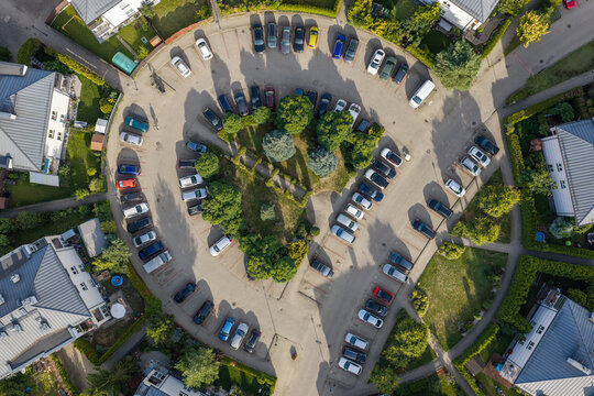 Aerial view of a curved parking lot surrounded by residential houses and green trees in Brwinow, Masovian Voivodeship, Poland.