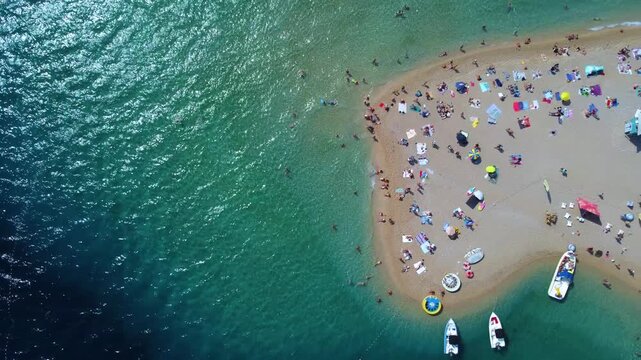 Aerial view of Golden Horn Beach with people relaxing on the sand and swimming in the clear turquoise sea in Bol, Split-Dalmatia County, Croatia.
