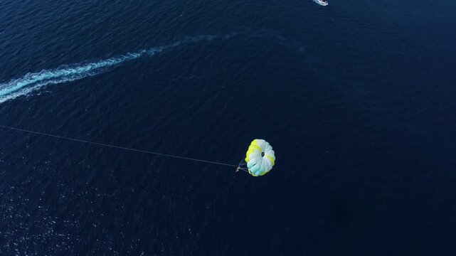 Aerial view of a colorful parasail being towed by a motorboat over the deep blue waters near Golden Horn Beach in Bol, Split-Dalmatia County, Croatia.